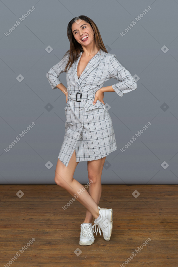 Cheerful young woman keeping arms akimbo and crossing her legs