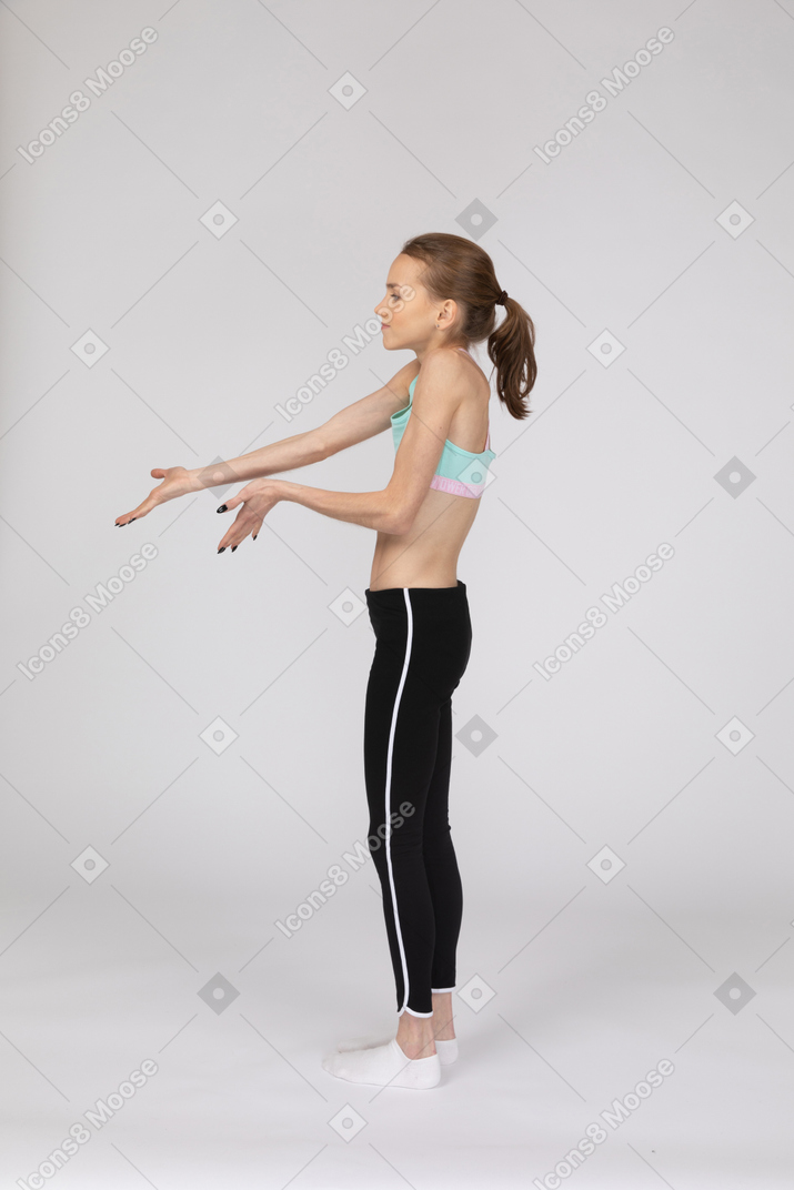 Vista lateral de una adolescente perpleja extendiendo sus manos
