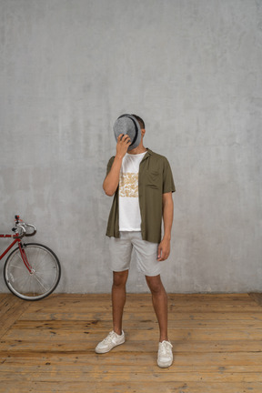 Man in casual clothes covering his face with a hat