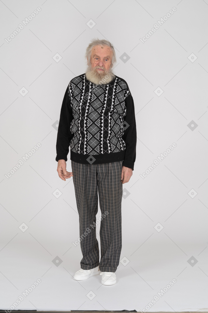 Displeased-looking elderly man standing with arms at side
