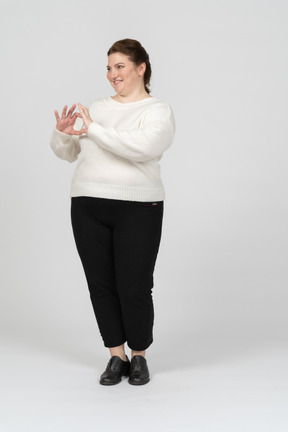 Mujer regordeta en suéter blanco que muestra la figura del corazón con sus dedos