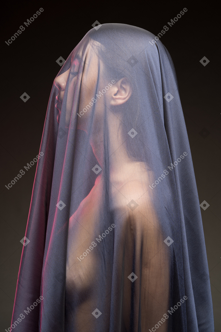 Side view of sensual naked young woman in dark veil with eyes closed