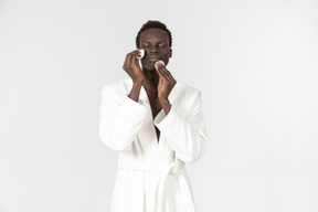 Jovem afroman limpeza rosto com almofadas de algodão