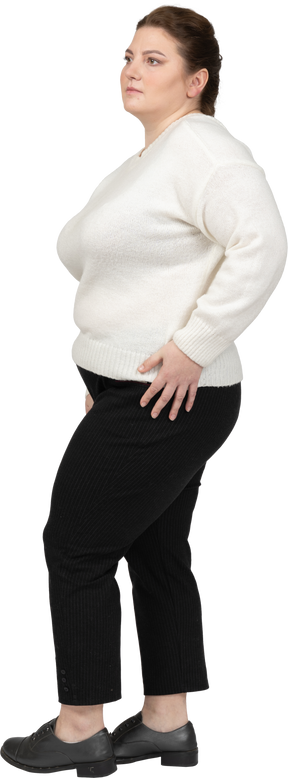 Mujer regordeta en suéter blanco posando con las manos en las caderas