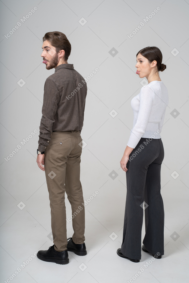 Vista traseira a três quartos de um jovem casal com roupas de escritório, mostrando a língua