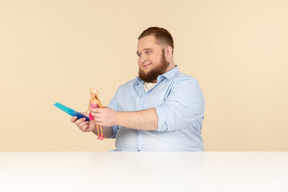 Big man holding hair brush and barbie doll