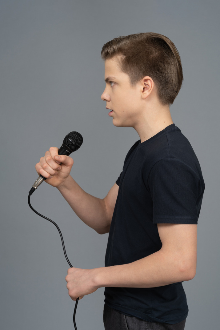 Young man speaking into a microphone sideways to camera