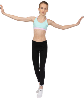Вид спереди девушки-подростка в спортивной одежде, балансирующей на цыпочках