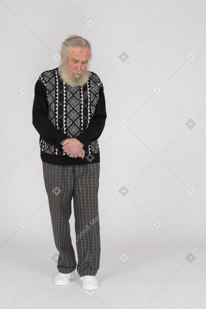 Uomo anziano in piedi con le mani giunte davanti e guardando in basso
