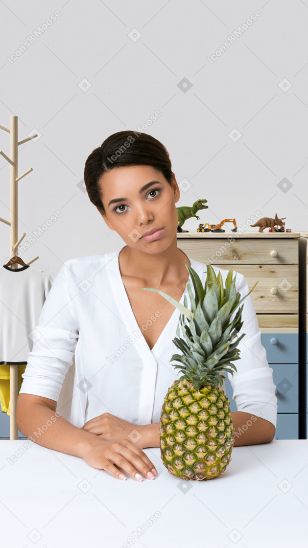 A woman sitting at a table with a pineapple in front of her
