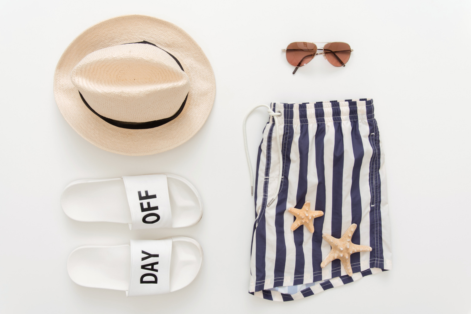 Striped man's bathing shorts, beach slippers, hat, sunglasses and sea shells