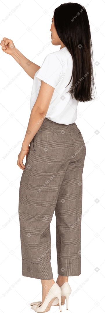 Vista posteriore di tre quarti di una giovane donna in calzoni che stringono il pugno