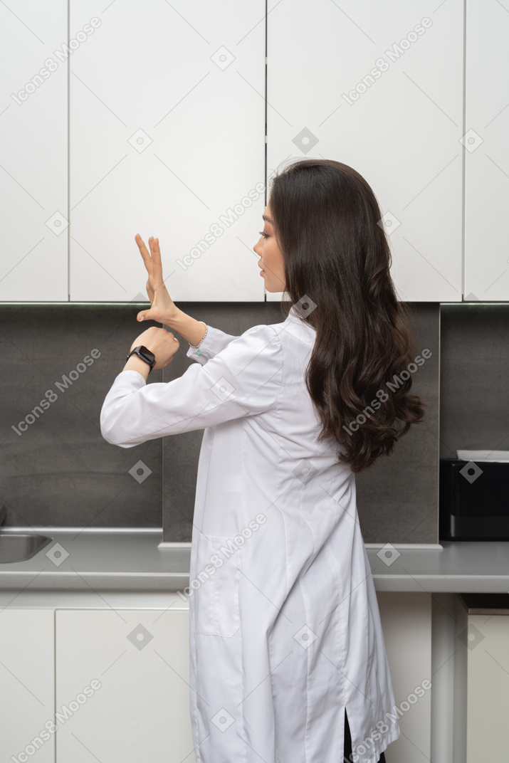 Woman wearing a laboratory coat using her smartwatch