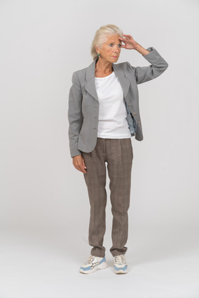 Vista frontal de una anciana en traje buscando a alguien