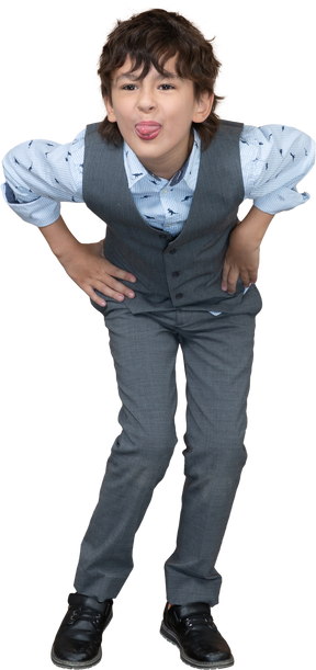 Front view of a boy in grey suit posing with hands on hips and showin tongue