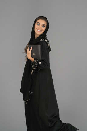 Una donna musulmana sorridente che tiene una borsetta