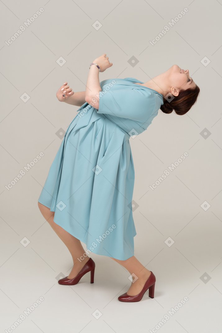 Side view of a woman in blue dress dancing