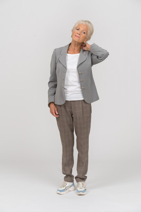Front view of an old lady in suit suffering from pain in neck