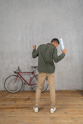 Back view of a man gesturing with fists and holding a map