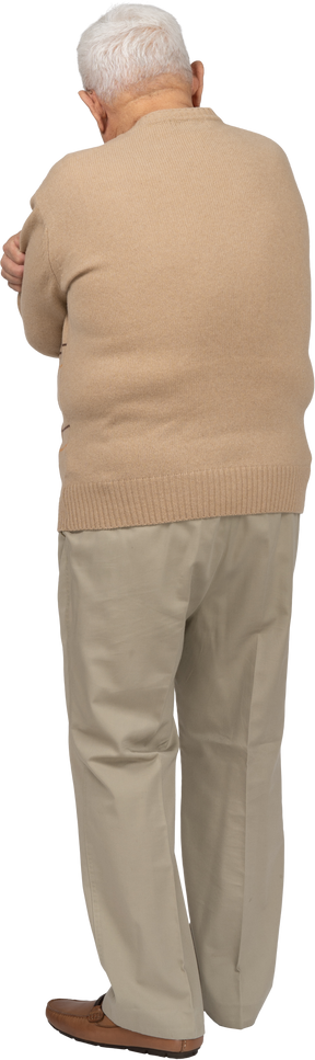 Rear view of an old man in casual clothes hugging himself