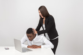 积极的女老板把她的员工的头拉进一台笔记本电脑