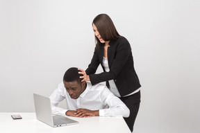 Aggressive female boss pulling her employee's head into a laptop