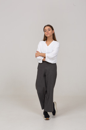 Vue de face d'une jeune femme autoritaire en vêtements de bureau marchant les bras croisés