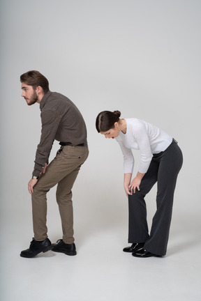 Vista lateral de um jovem casal com roupas de escritório tocando o joelho