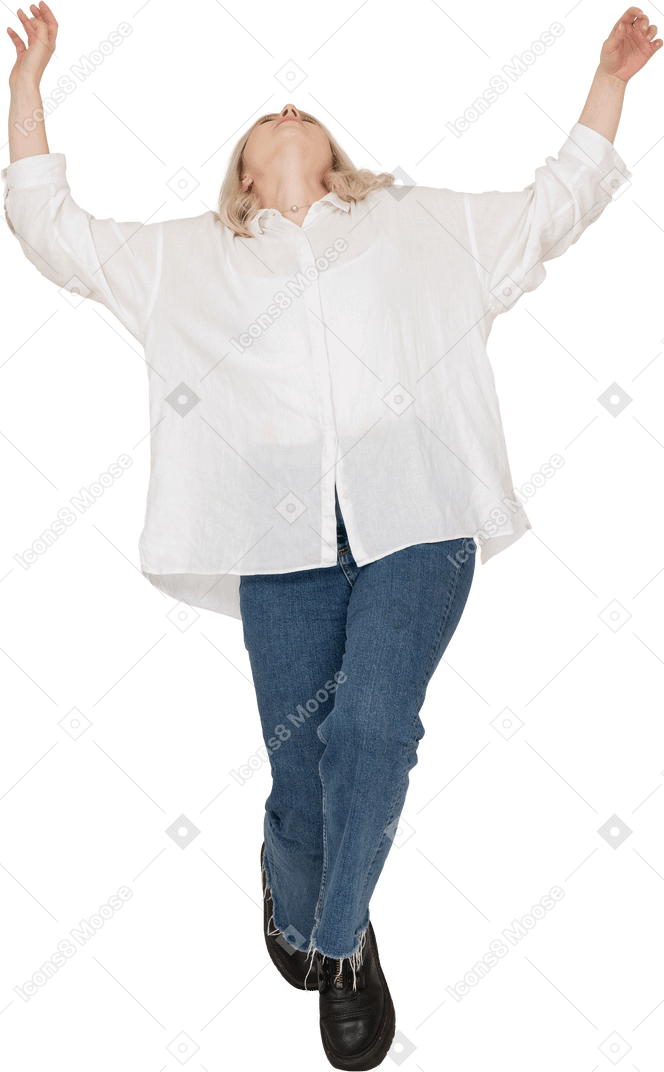 Vista frontal de una mujer rubia en ropa casual de puntillas cayendo y levantando las manos