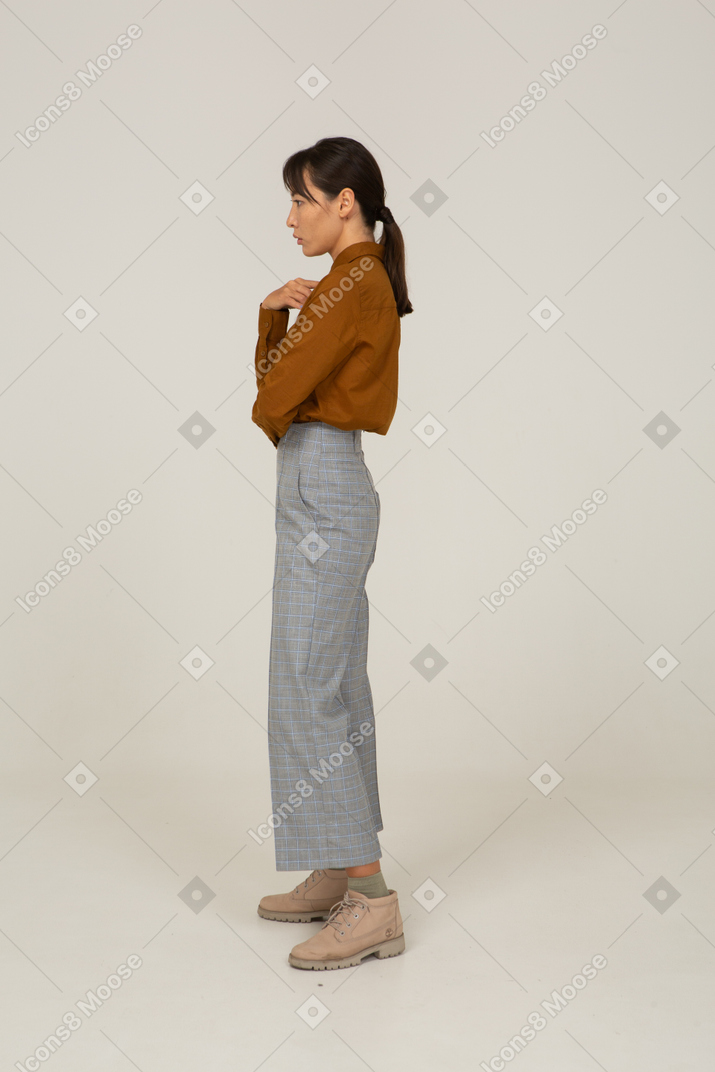 Side view of a thoughtful young asian female in breeches and blouse