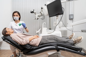Toute la longueur d'une femme dentiste faisant un dossier dentaire à sa patiente dans une armoire d'hôpital