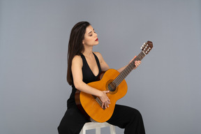 Young woman enjoying playing a guitar