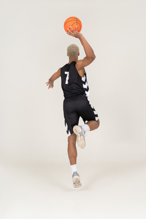 Vista posterior de un joven jugador de baloncesto masculino anotando un punto