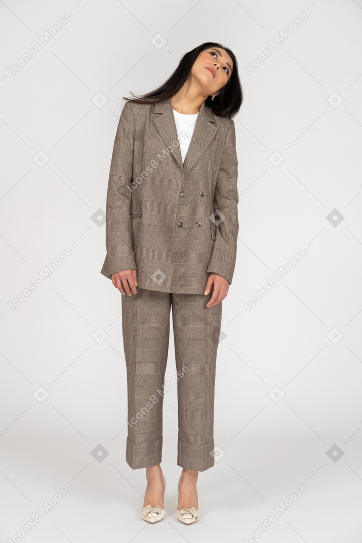 Front view of a young lady in brown business suit tilting head while looking up