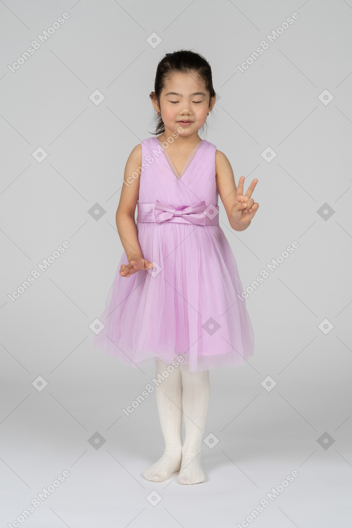 Portrait of a little girl making peace sign with eyes closed