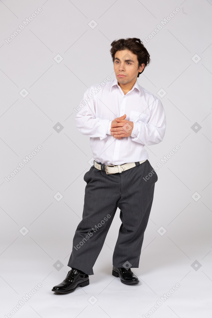 Задумчивый мужчина в деловой повседневной одежде стоит со сложенными руками