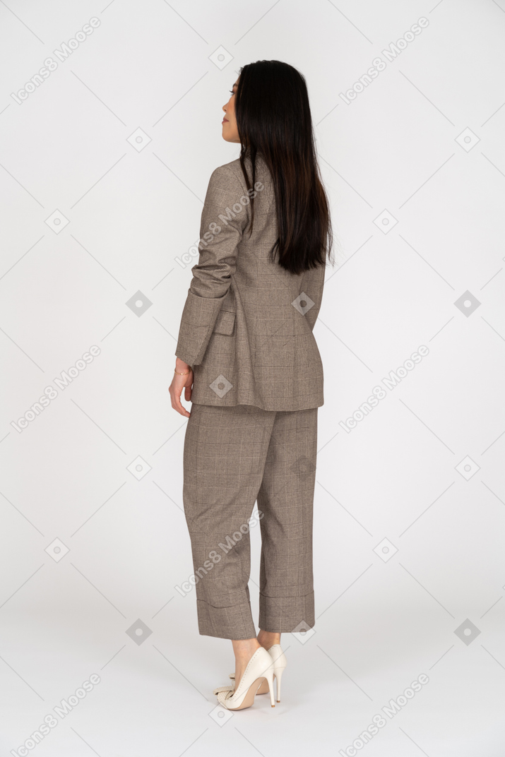脇を見て茶色のビジネススーツを着た若い女性の4分の3の背面図