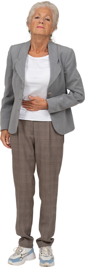 Vista frontal de una anciana en traje que sufre de dolor de estómago