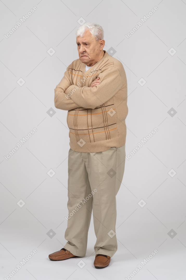 Side view of an old man in casual clothes standing with crossed arms