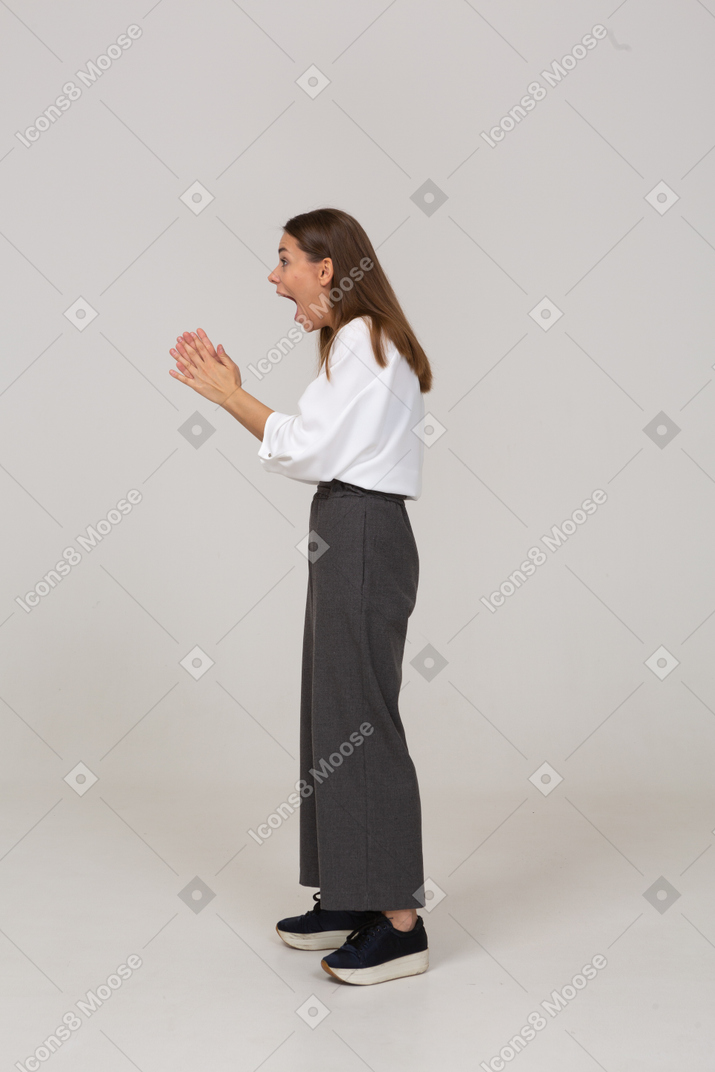 Side view of an excited young lady in office clothing raising hands