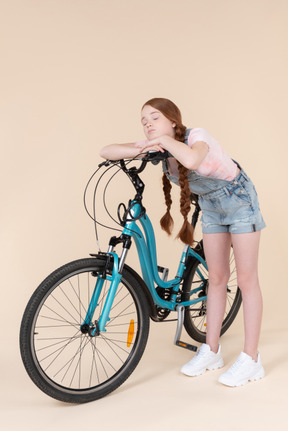 Bored looking teenage girl leaning on bicycle