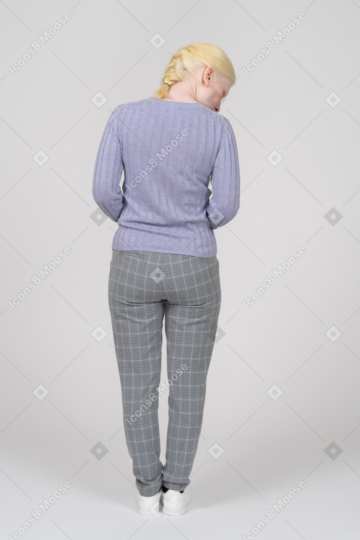 Вид сзади на молодую женщину в повседневной одежде, выглядящую правильно