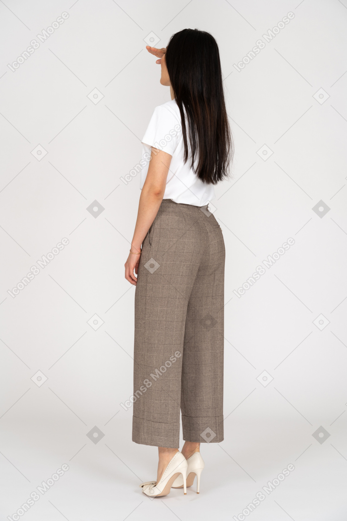 Three-quarter back view of a young woman in breeches looking for something