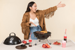 Jovem mulher asiática preparando um churrasco e exclamando algo