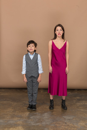 Vista frontal de um menino e uma mulher sorrindo com um vestido vermelho