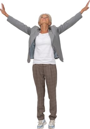Front view of an old lady in suit standing on toes and putting hands up