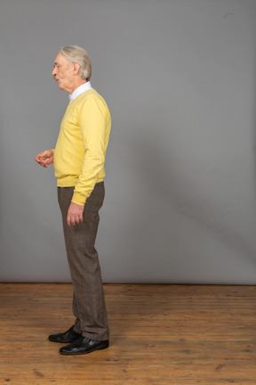 Side view of a thoughtful old man raising hand