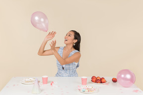 Junge asiatische frau, die geburtstag feiert und mit ballon spielt