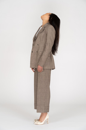 頭を傾けながら背を向ける茶色のビジネススーツの若い女性の側面図