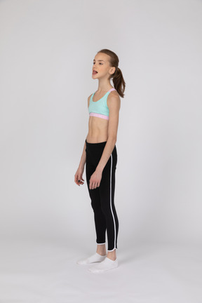 Side view of a teen girl in sportswear raising hand and arguing